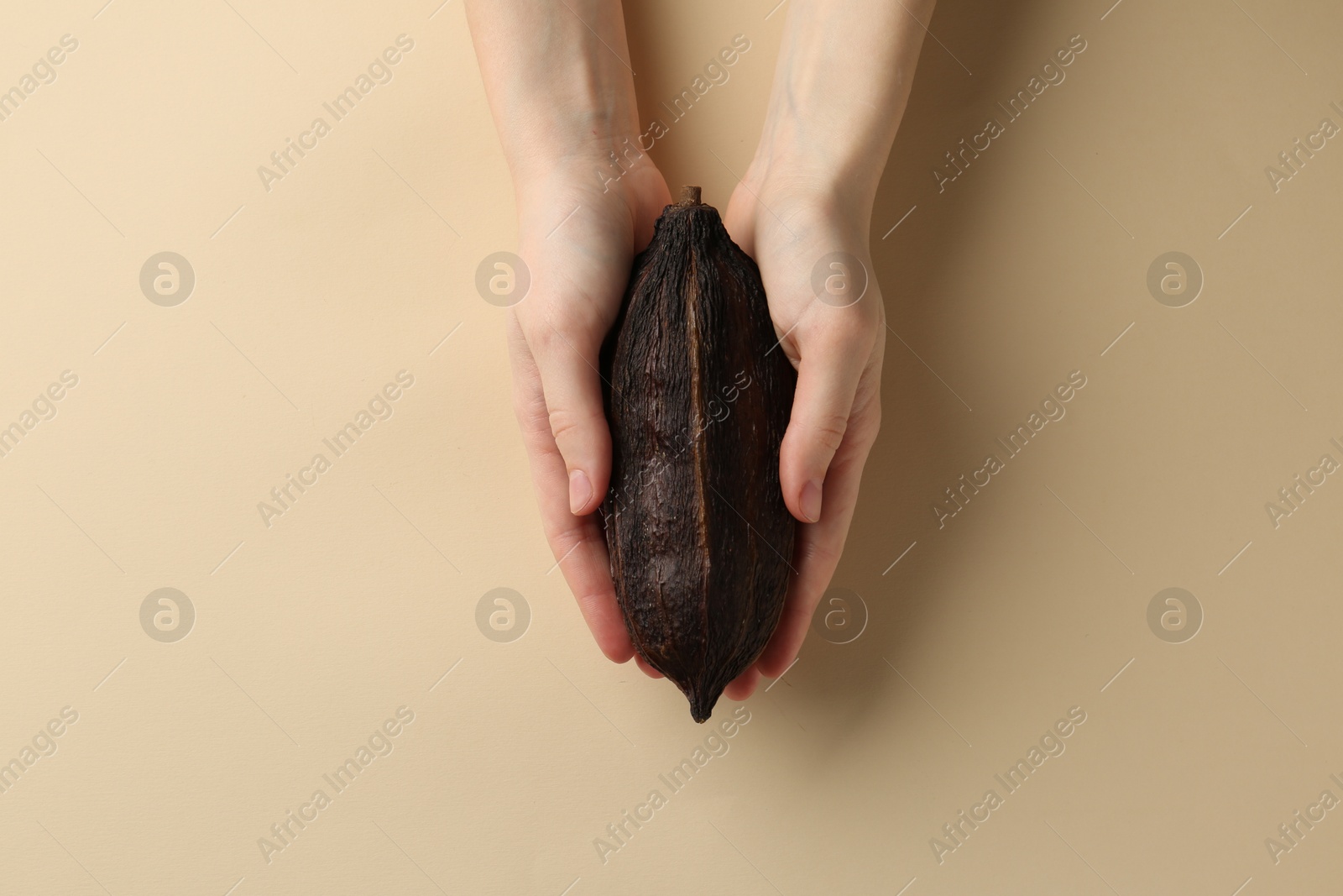 Photo of Woman with cocoa pod on beige background, top view