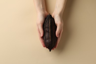 Photo of Woman with cocoa pod on beige background, top view