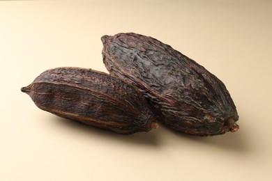 Photo of Whole tropical cocoa pods on beige background