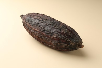 Photo of Whole tropical cocoa pod on beige background