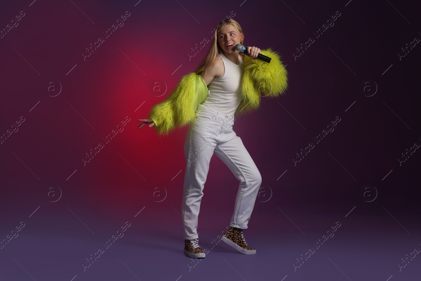 Photo of Talented singer in faux fur performing on dark background with pink light