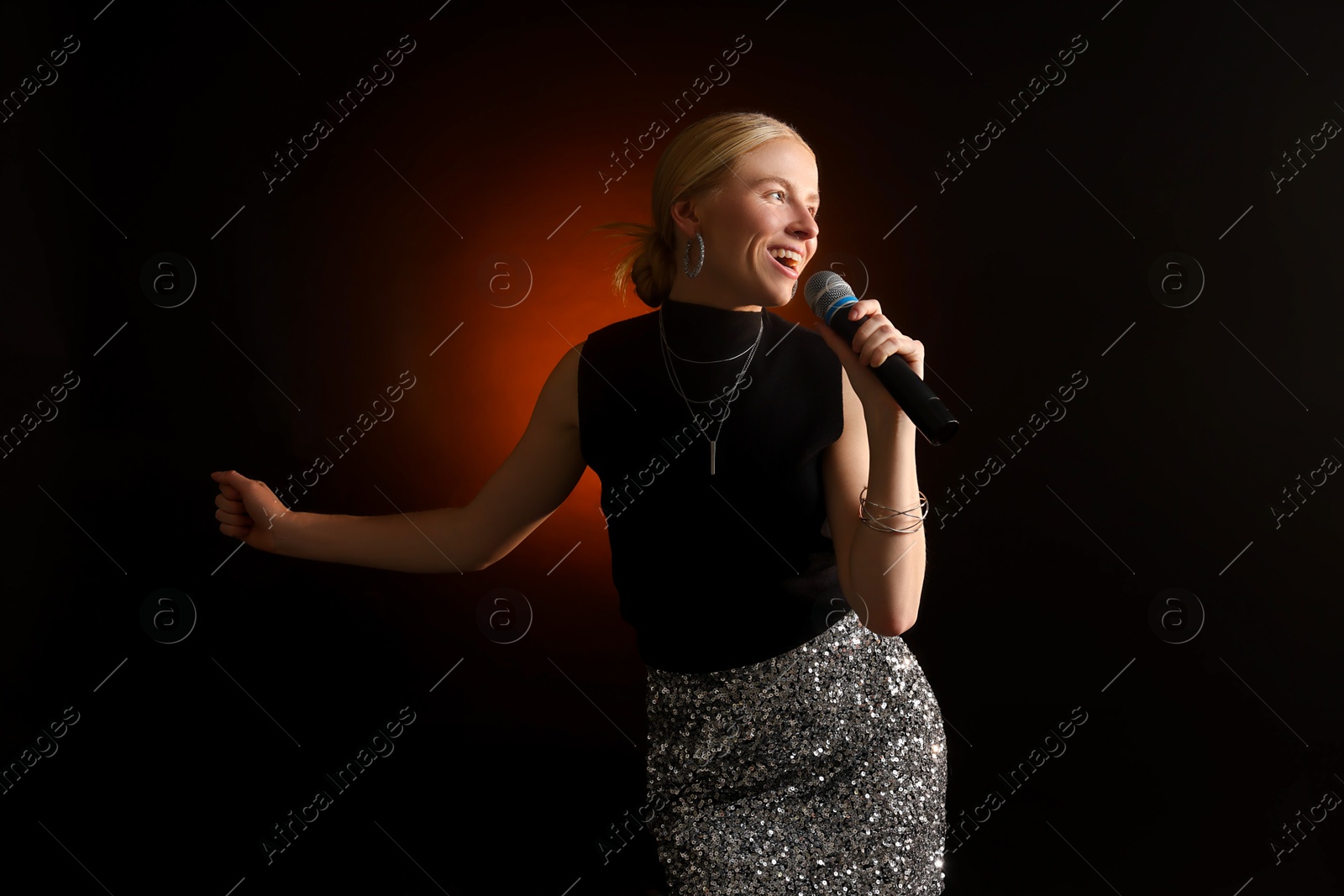 Photo of Beautiful singer performing on dark background with color light