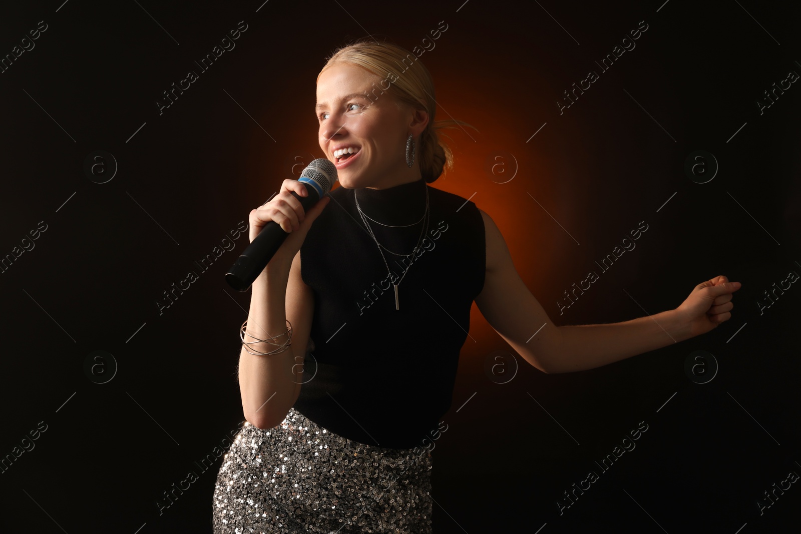 Photo of Beautiful singer performing on dark background with color light