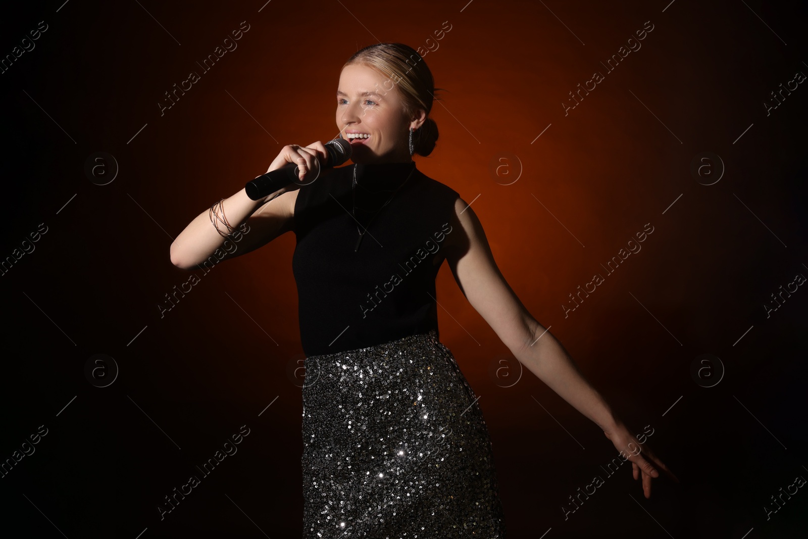 Photo of Beautiful singer performing on dark background with color light