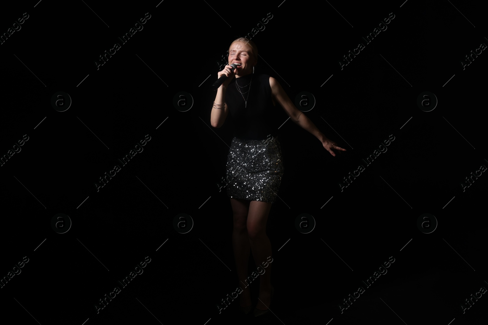 Photo of Beautiful talented singer performing on black background