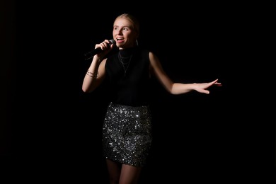 Photo of Beautiful talented singer performing on black background