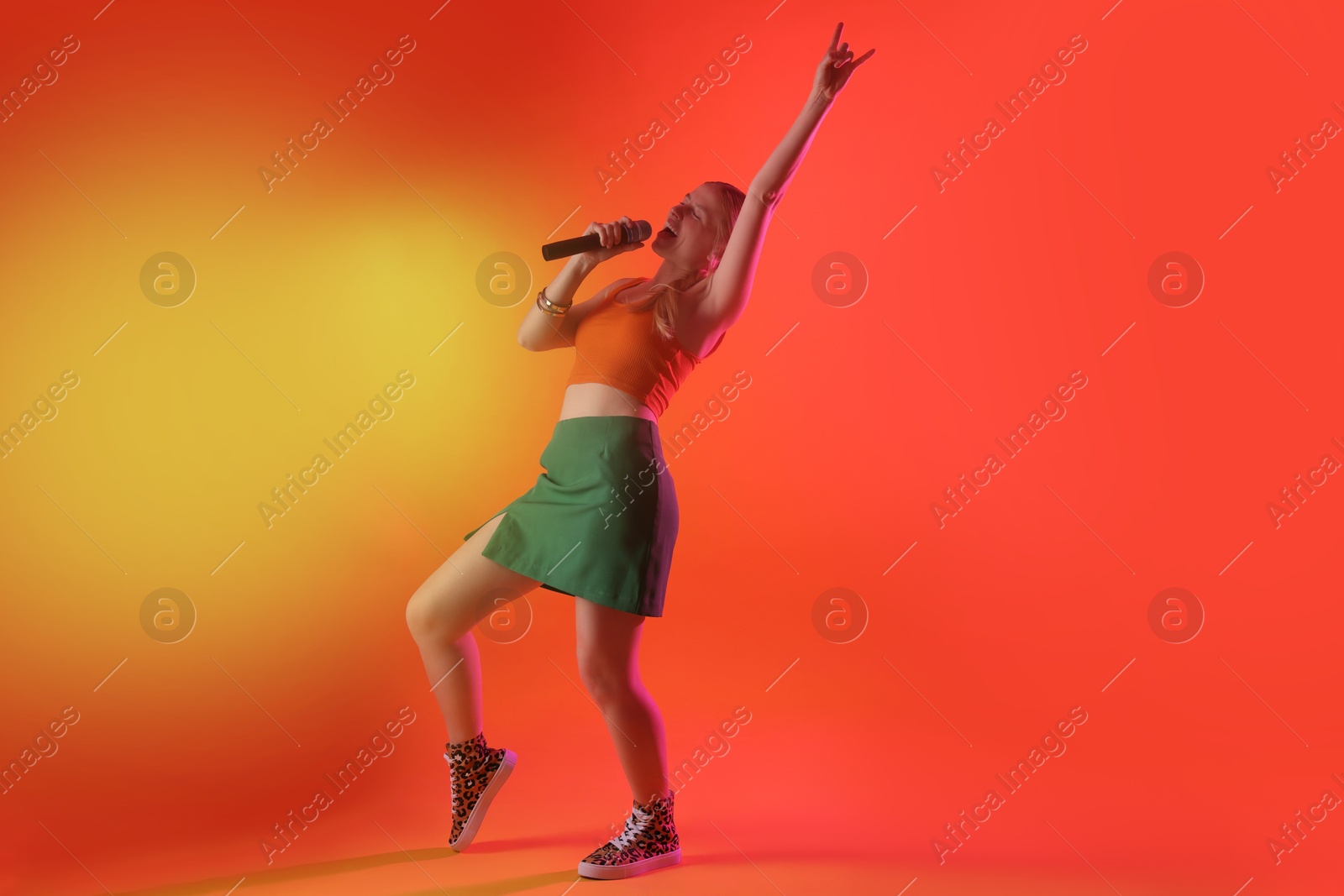 Photo of Talented singer performing on red background with yellow light