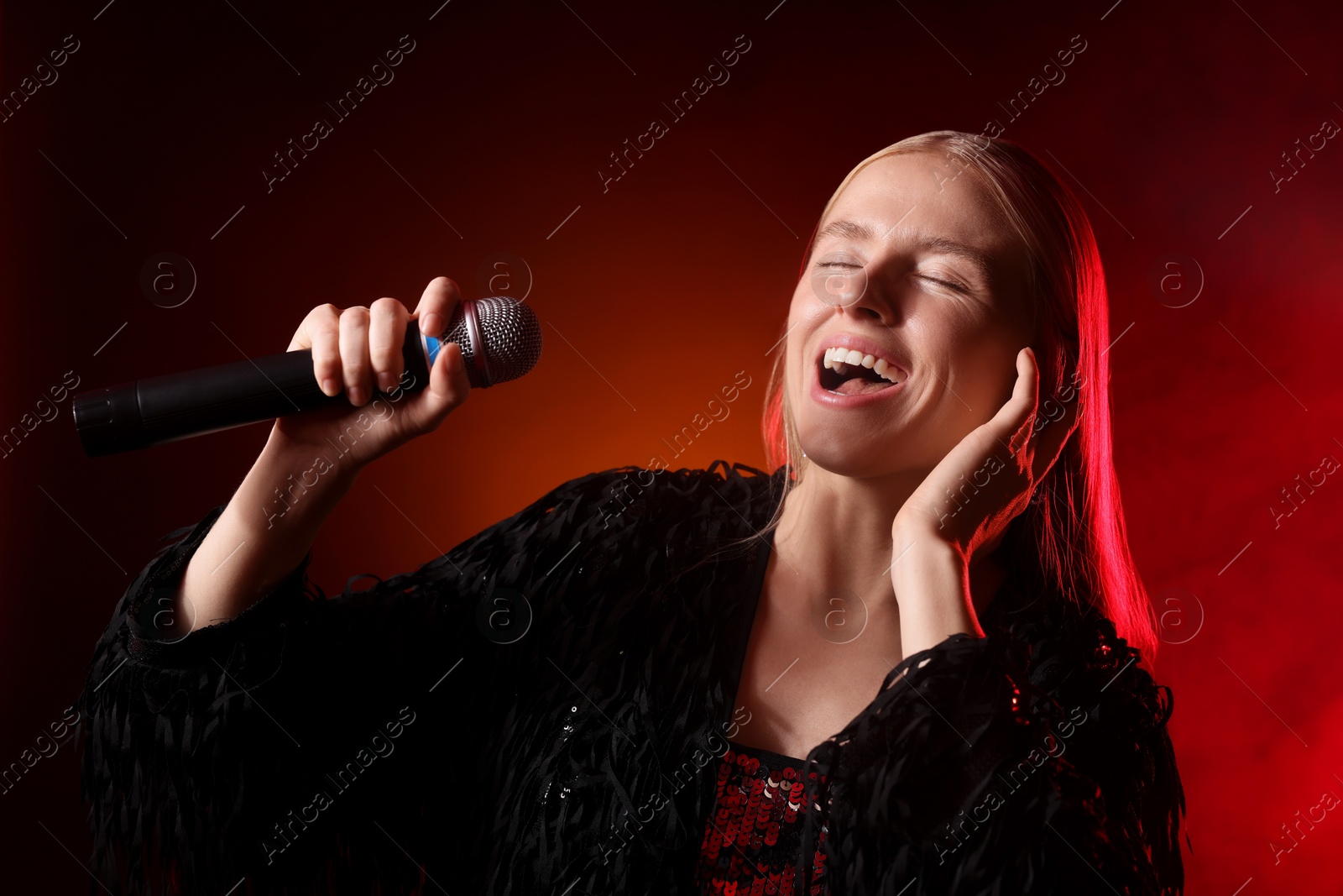 Photo of Beautiful singer performing on dark background with orange light