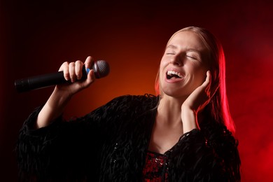 Photo of Beautiful singer performing on dark background with orange light