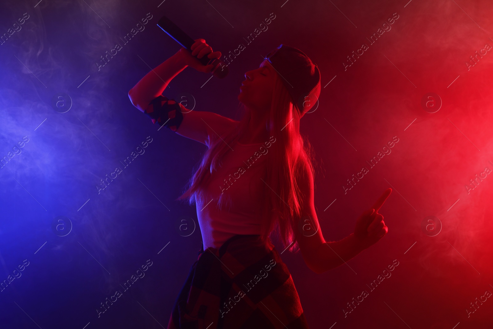 Photo of Talented singer performing on dark background with color lights