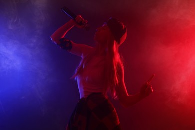 Photo of Talented singer performing on dark background with color lights