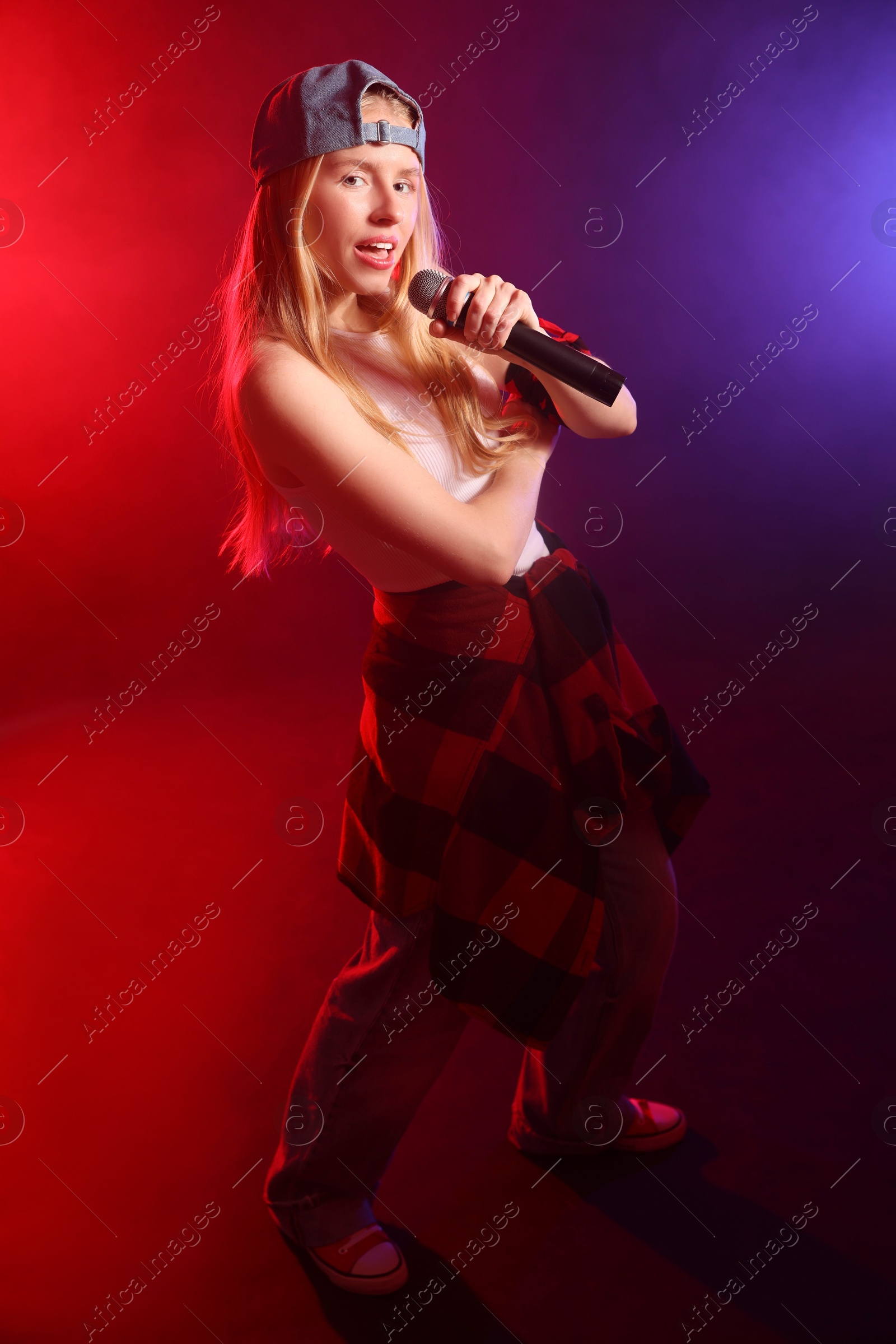 Photo of Talented singer performing on dark background with color lights