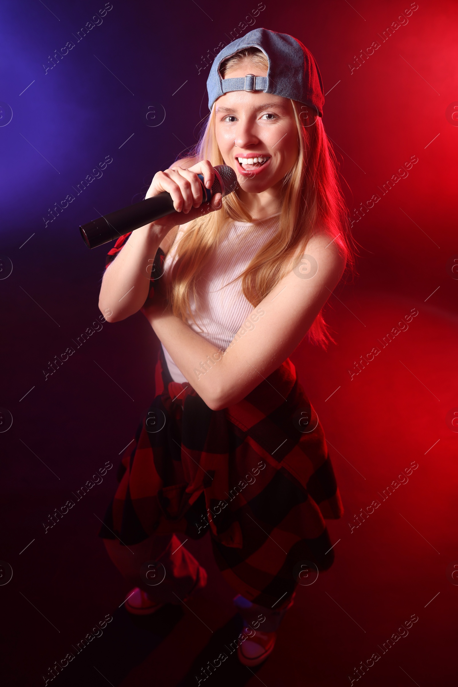 Photo of Talented singer performing on dark background with color lights