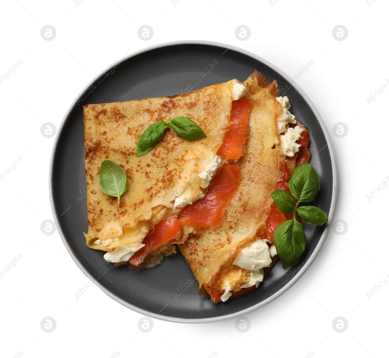 Photo of Delicious crepes with salmon, cream cheese and basil isolated on white, top view