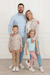 Photo of Happy parents and their children near white wall indoors