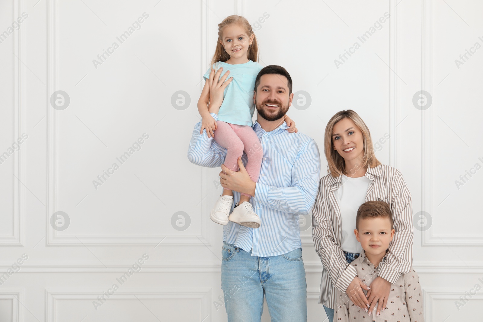 Photo of Happy parents and their children near white wall indoors, space for text