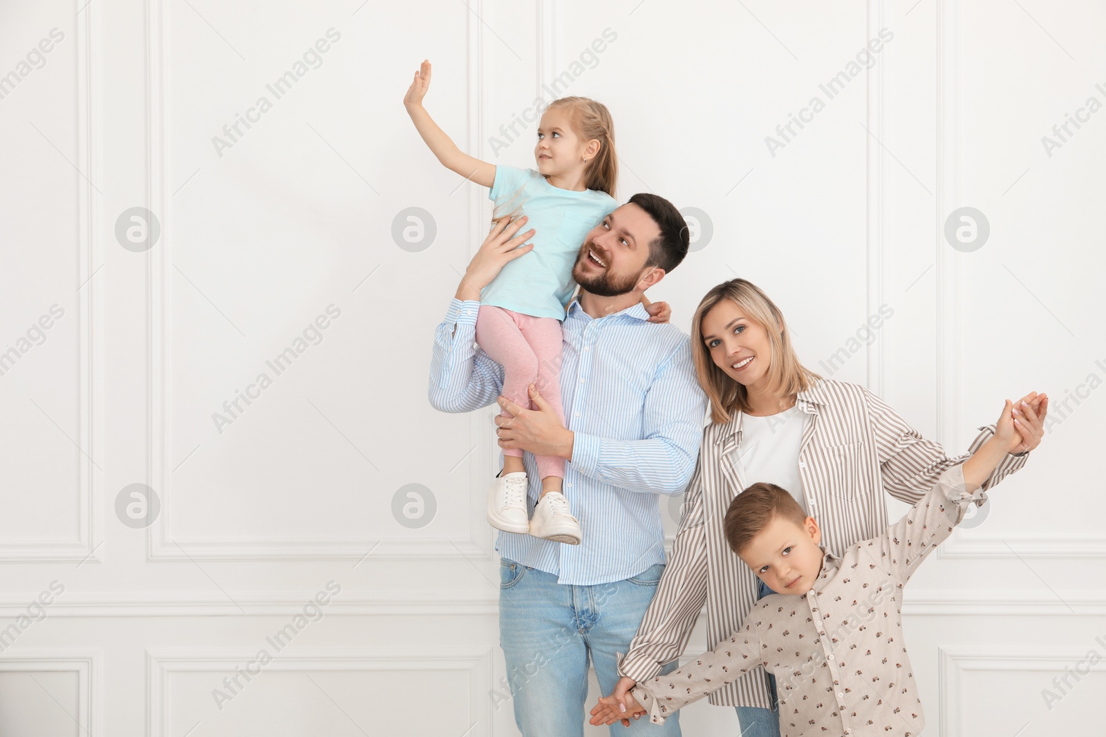 Photo of Happy parents and their children near white wall indoors, space for text