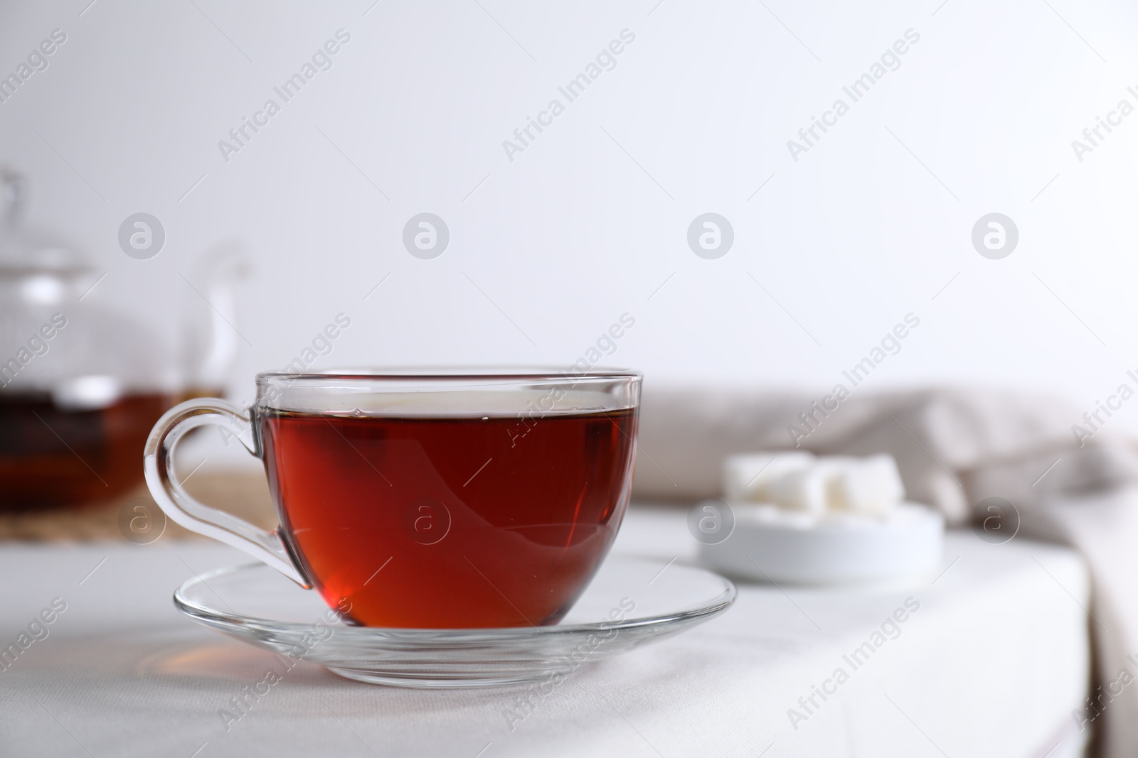 Photo of Refreshing black tea in cup on light table. Space for text