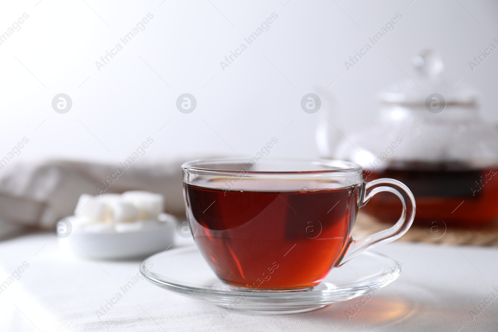 Photo of Refreshing black tea in cup on light table. Space for text