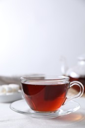 Photo of Refreshing black tea in cup on light table. Space for text