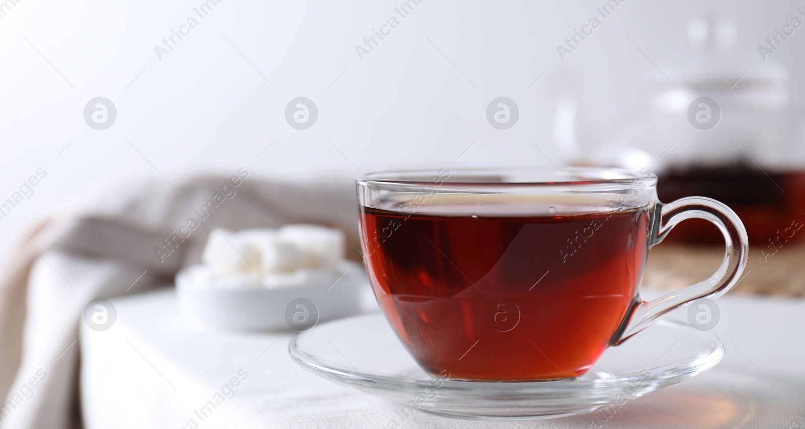 Photo of Refreshing black tea in cup on light table, closeup. Space for text