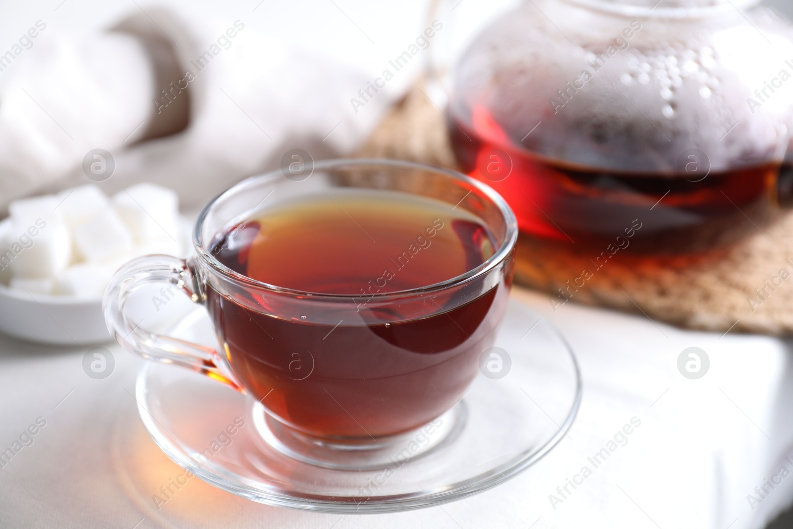 Photo of Refreshing black tea in cup on light table, closeup