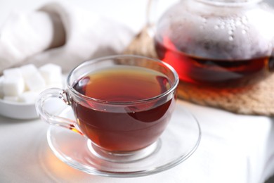 Photo of Refreshing black tea in cup on light table, closeup