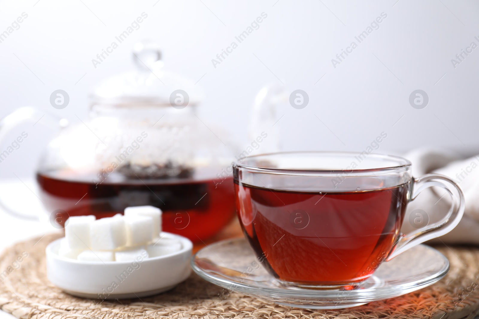 Photo of Refreshing black tea in cup and sugar on light table