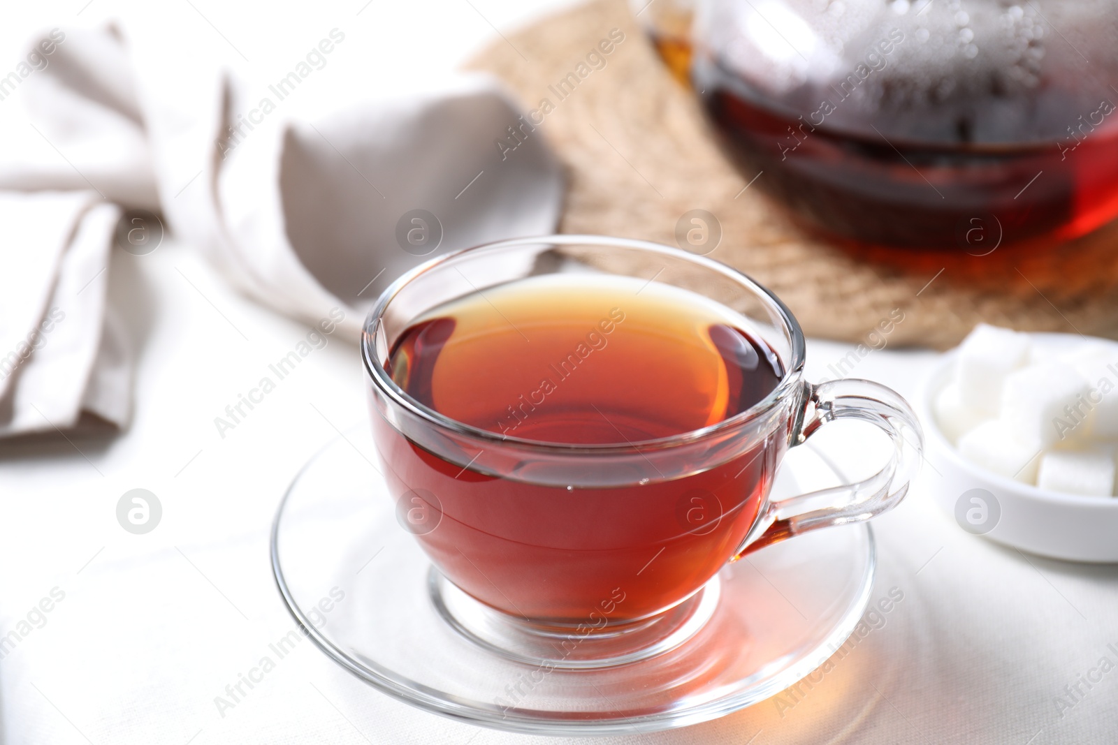 Photo of Refreshing black tea in cup on light table, closeup