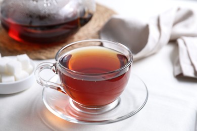 Photo of Refreshing black tea in cup on light table, closeup