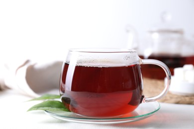 Photo of Refreshing black tea in cup on light table, closeup