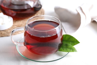 Photo of Refreshing black tea in cup on light table, closeup