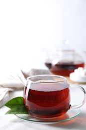 Photo of Refreshing black tea in cup on light table. Space for text