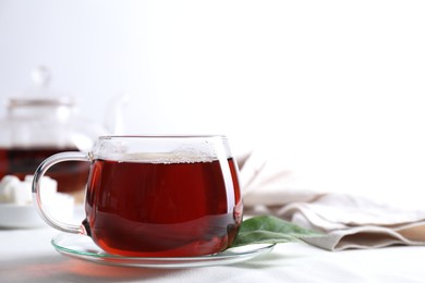 Photo of Refreshing black tea in cup on light table. Space for text