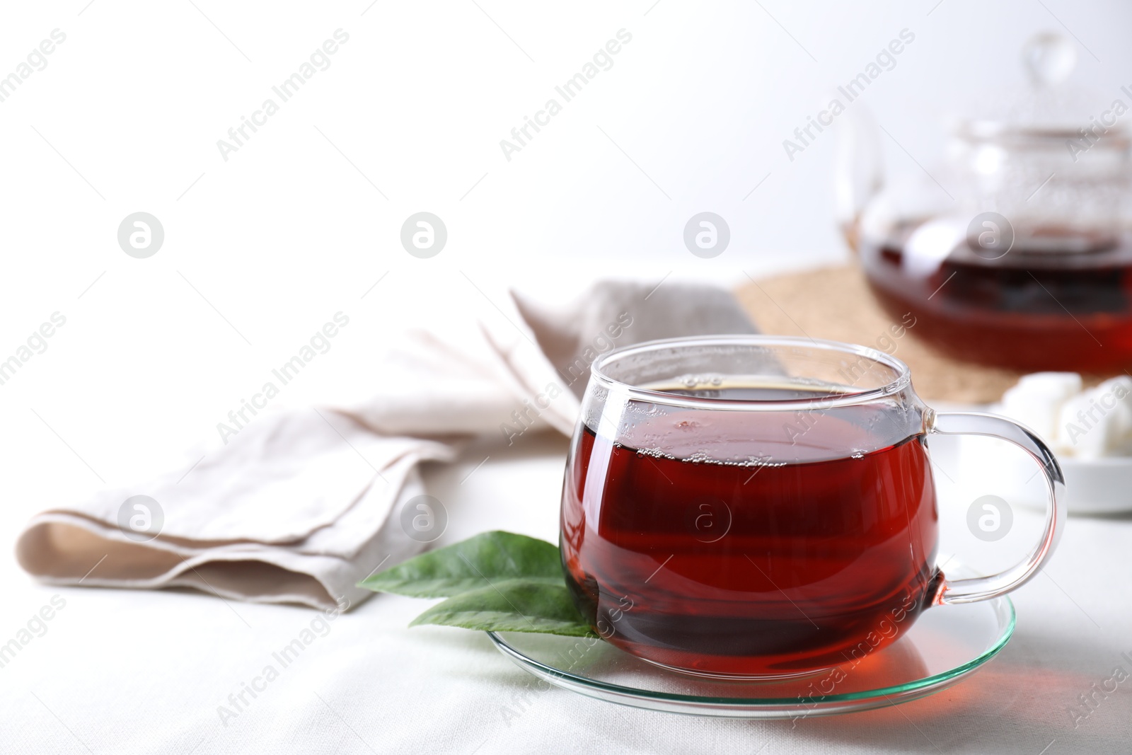 Photo of Refreshing black tea in cup on light table. Space for text