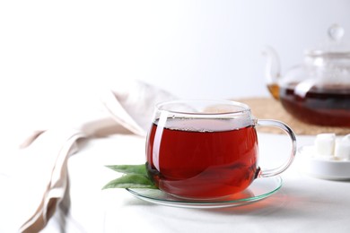 Photo of Refreshing black tea in cup on light table. Space for text