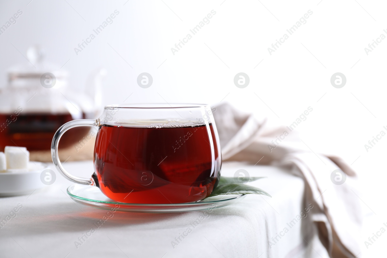 Photo of Refreshing black tea in cup on light table. Space for text