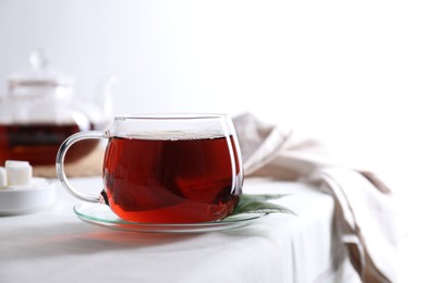 Photo of Refreshing black tea in cup on light table. Space for text