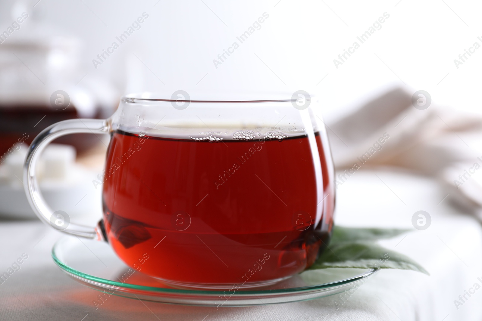 Photo of Refreshing black tea in cup on light table, closeup