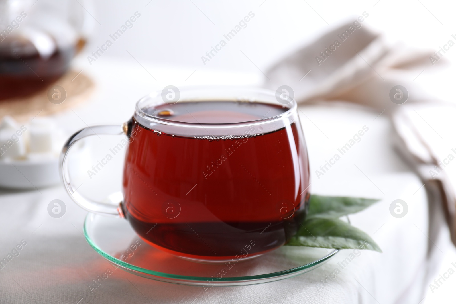 Photo of Refreshing black tea in cup on light table, closeup