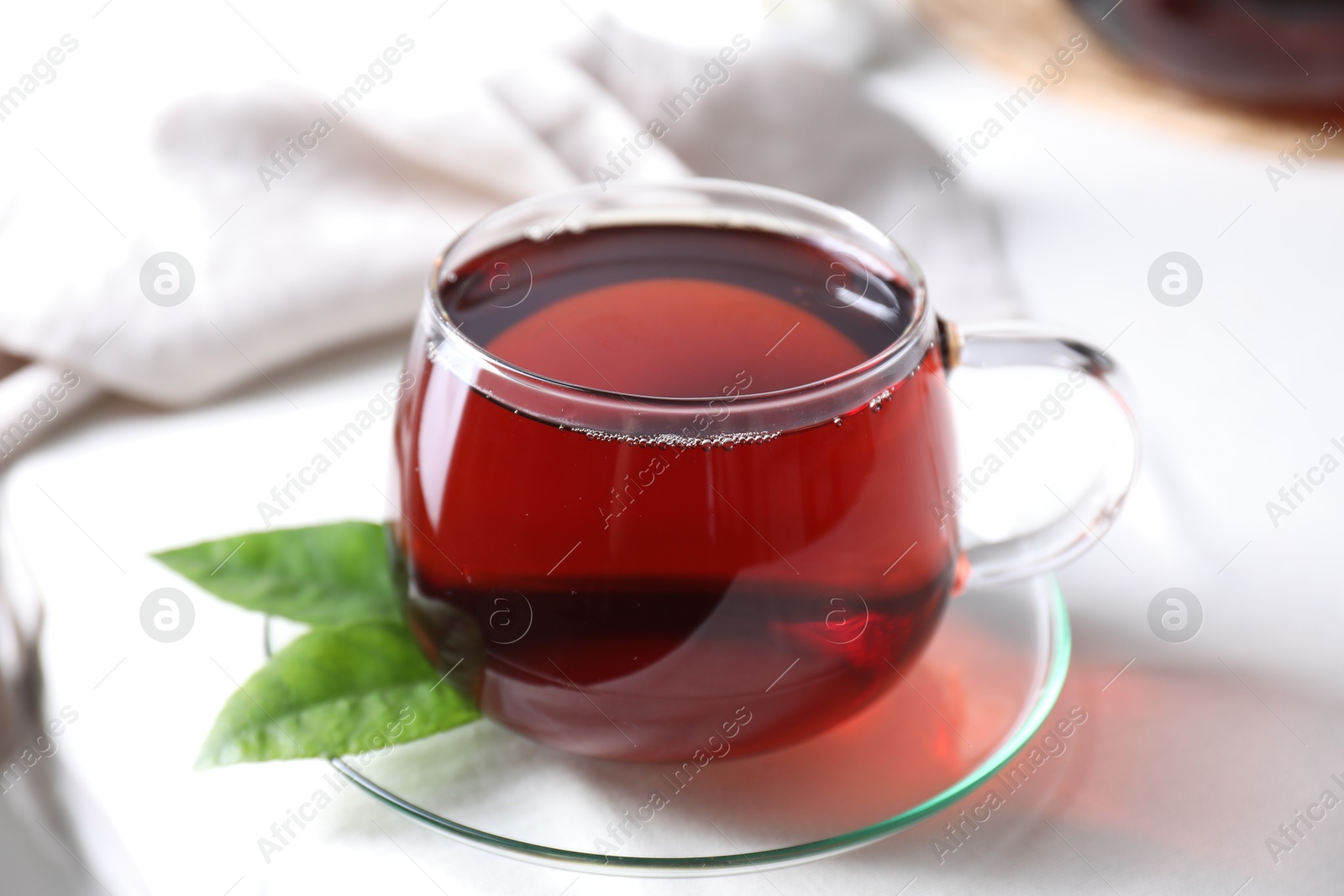 Photo of Refreshing black tea in cup on light table, closeup