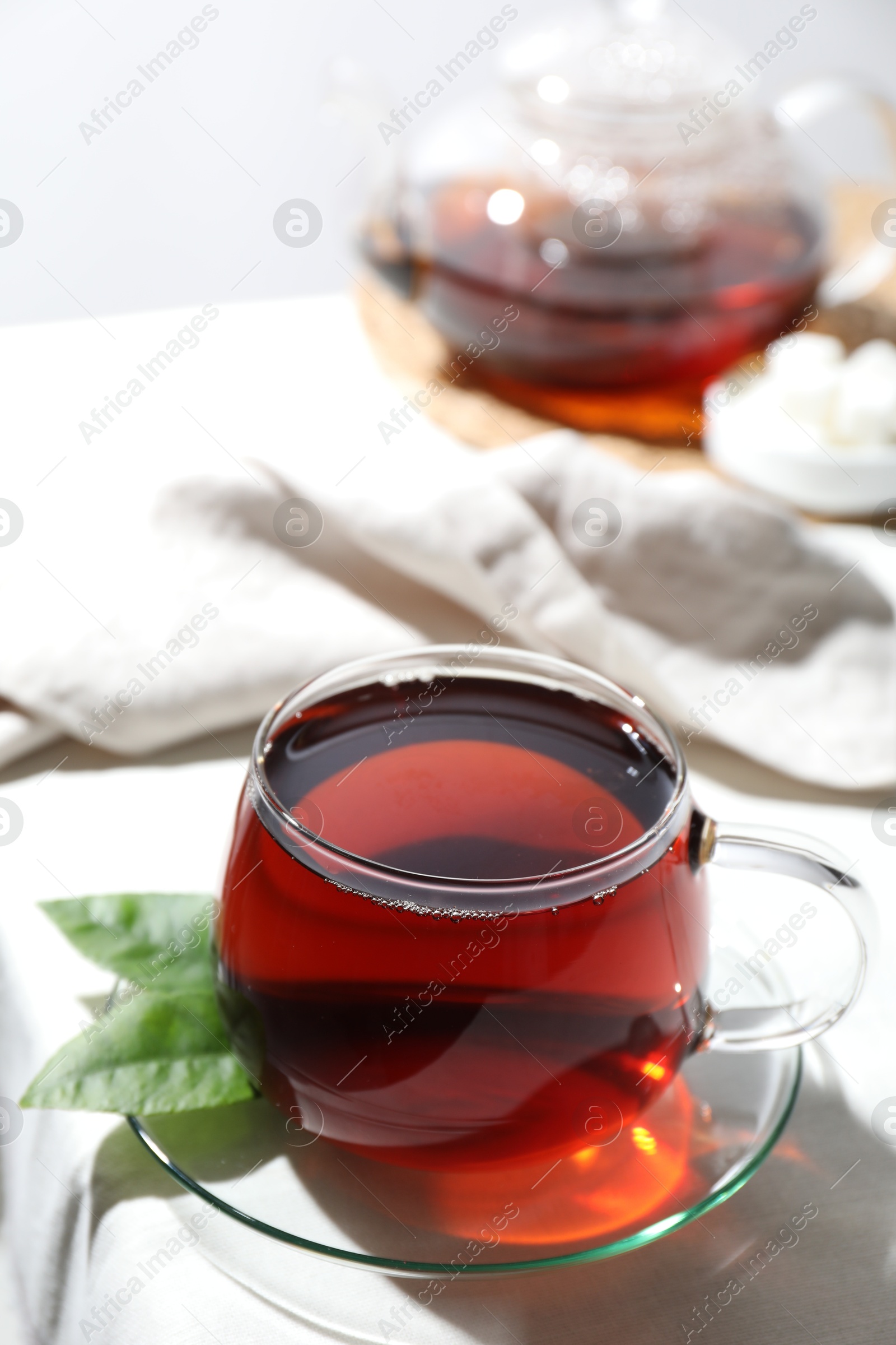 Photo of Refreshing black tea in cup on light table, closeup