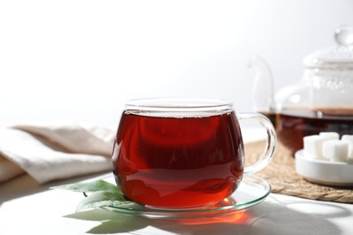 Photo of Refreshing black tea in cup on light table, closeup