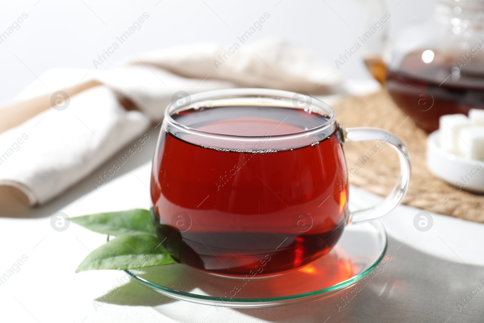 Photo of Refreshing black tea in cup on light table, closeup