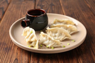 Photo of Tasty gyoza (dumplings) and soy sauce on wooden table, closeup