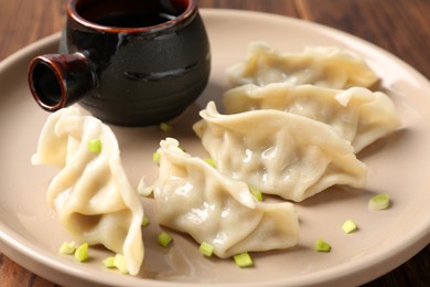 Photo of Tasty gyoza (dumplings) and soy sauce on table, closeup