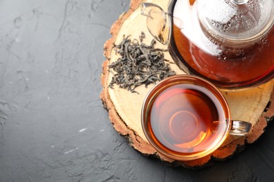 Photo of Aromatic black tea in cup and dry leaves on grey table, top view. Space for text