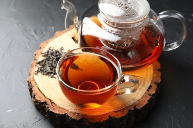 Photo of Aromatic black tea and dry leaves on grey table, closeup