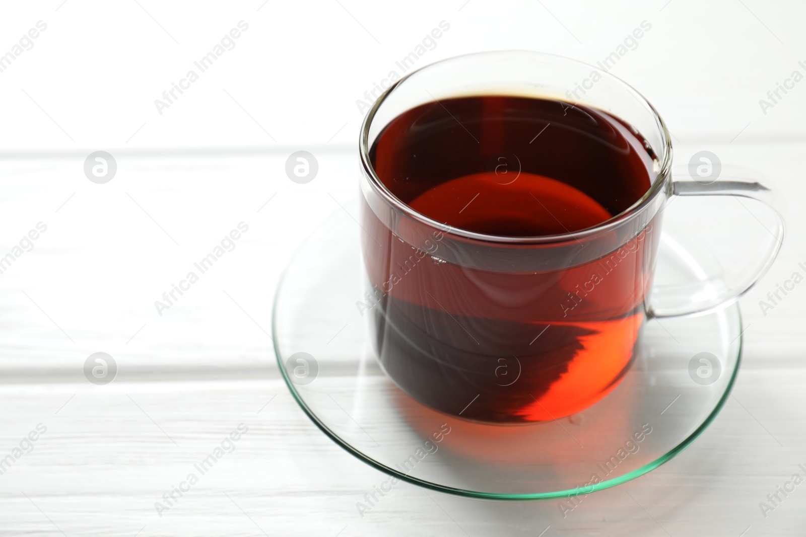 Photo of Aromatic black tea in cup on white wooden table, closeup. Space for text