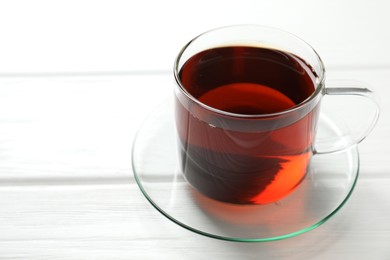 Photo of Aromatic black tea in cup on white wooden table, closeup. Space for text